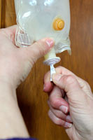 Protect the cleanliness of the entry port by not touching it. Remove the cover from the fluid bag’s entry port.