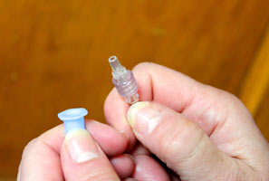 Do not touch the end of the fluid line once the cap is removed. Twist and pull to remove the plastic cap from the end of the fluid line.