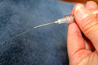 Running fluid through the line removes air from the system. Hold the uncapped needle over a bowl to allow fluid to run through.